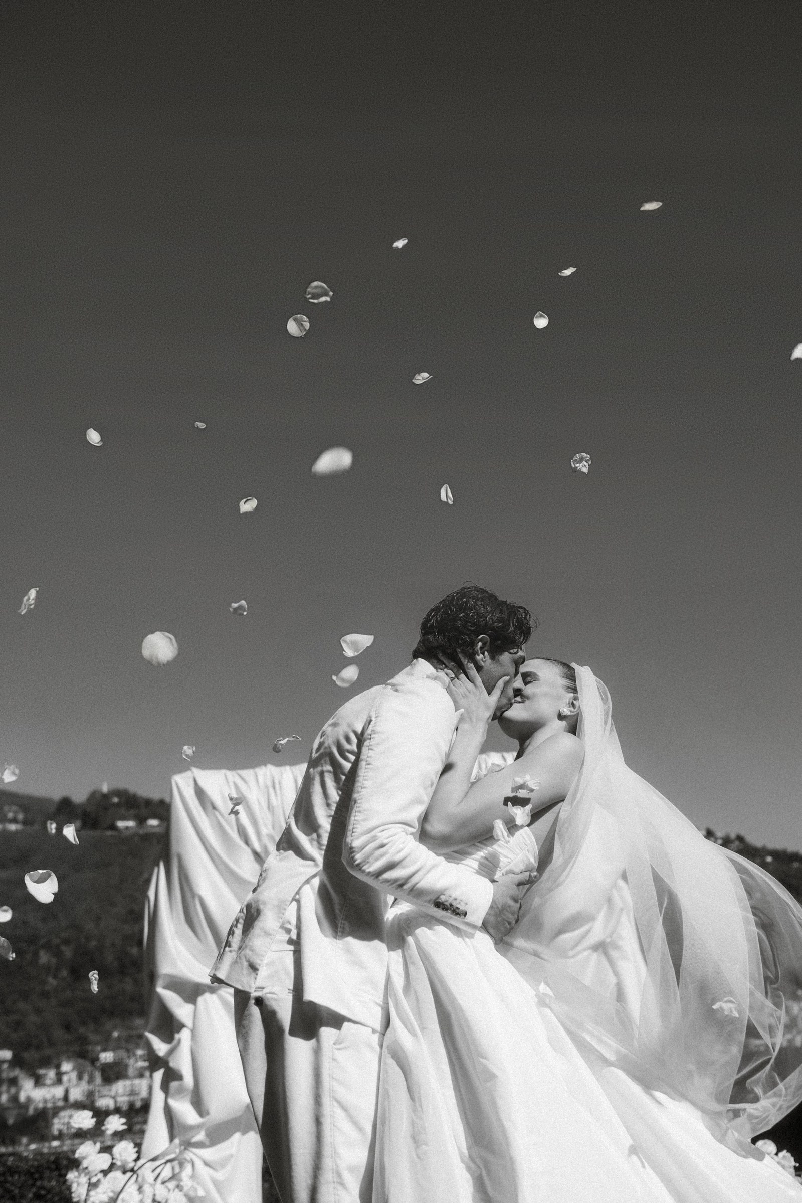 A couple walking beneath falling petals at Villa Revel Parravicini